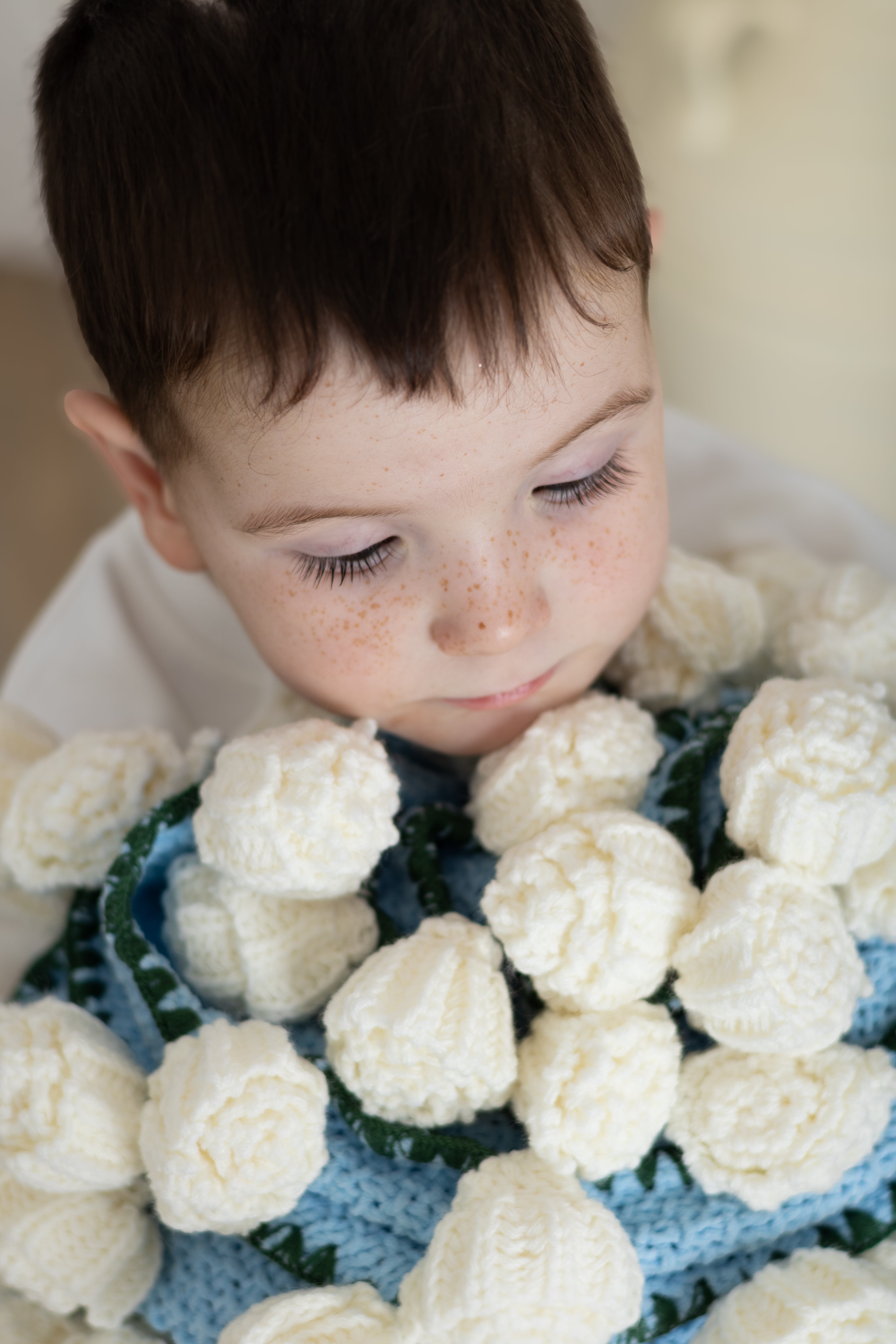Child surrounded by white flowers on a blue blanket